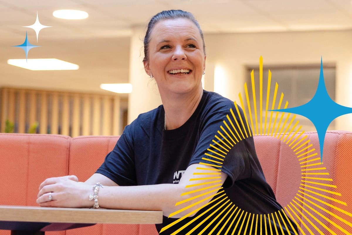 Woman sitting at a table, smiling, with abstract graphic shapes overlaid on the image.