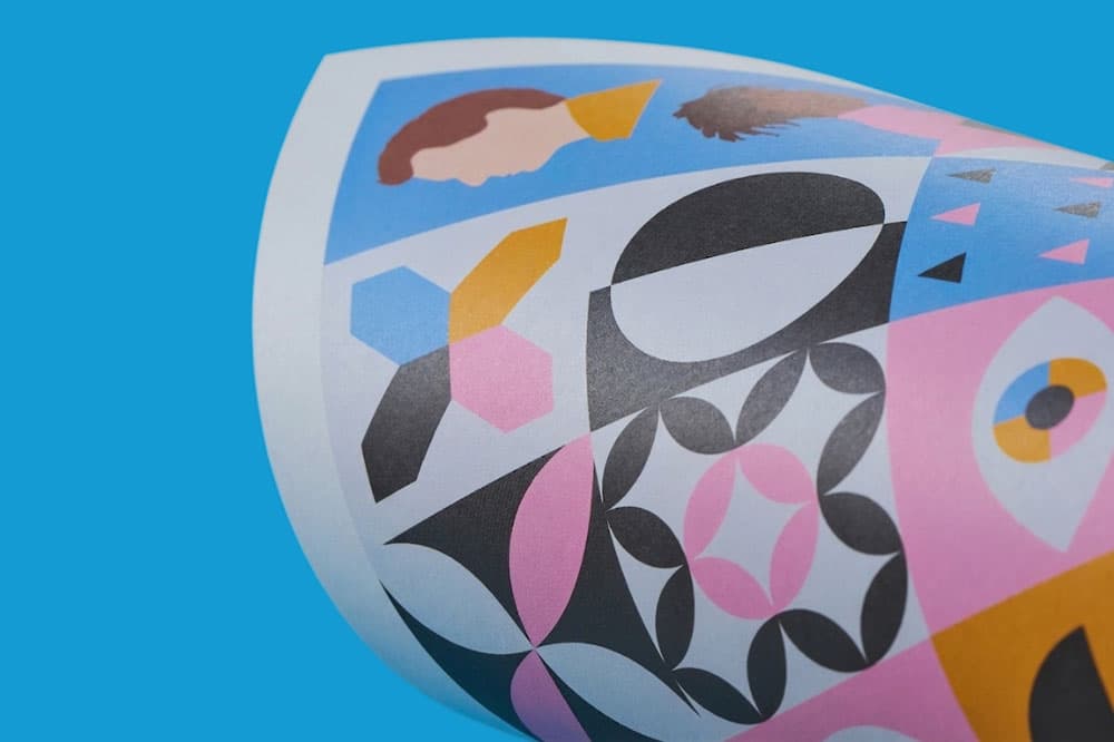 Curved sheet with colourful abstract geometric and face illustrations on a blue background.