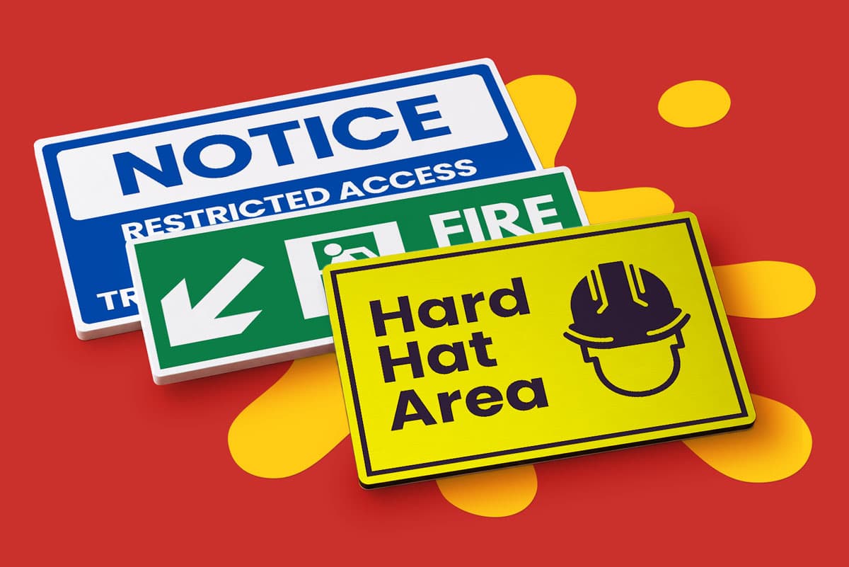 Three safety signs: "Notice", "Fire Exit", and "Hard Hat Area" on a red background.