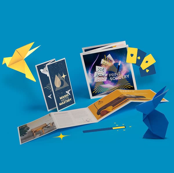 Magic-themed brochures, origami birds, playing cards, and a wand on a blue background.