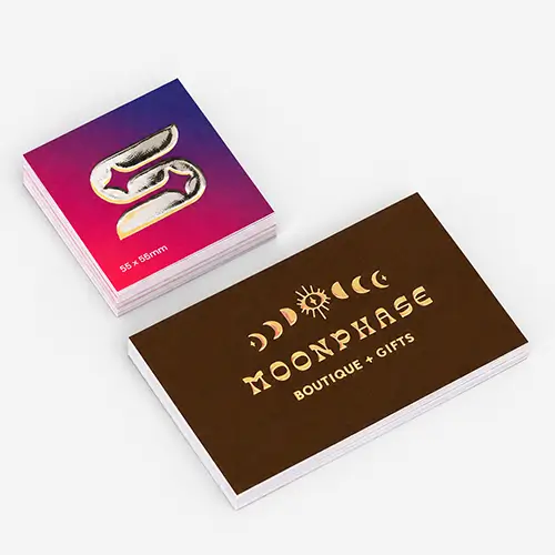 Two stacks of business cards, one with a silver metallic foil icon, one with gold foil "Moonphase Boutique + Gifts.