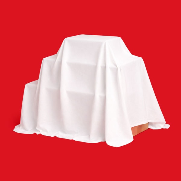A white cloth draped over an unknown object against a solid red background.