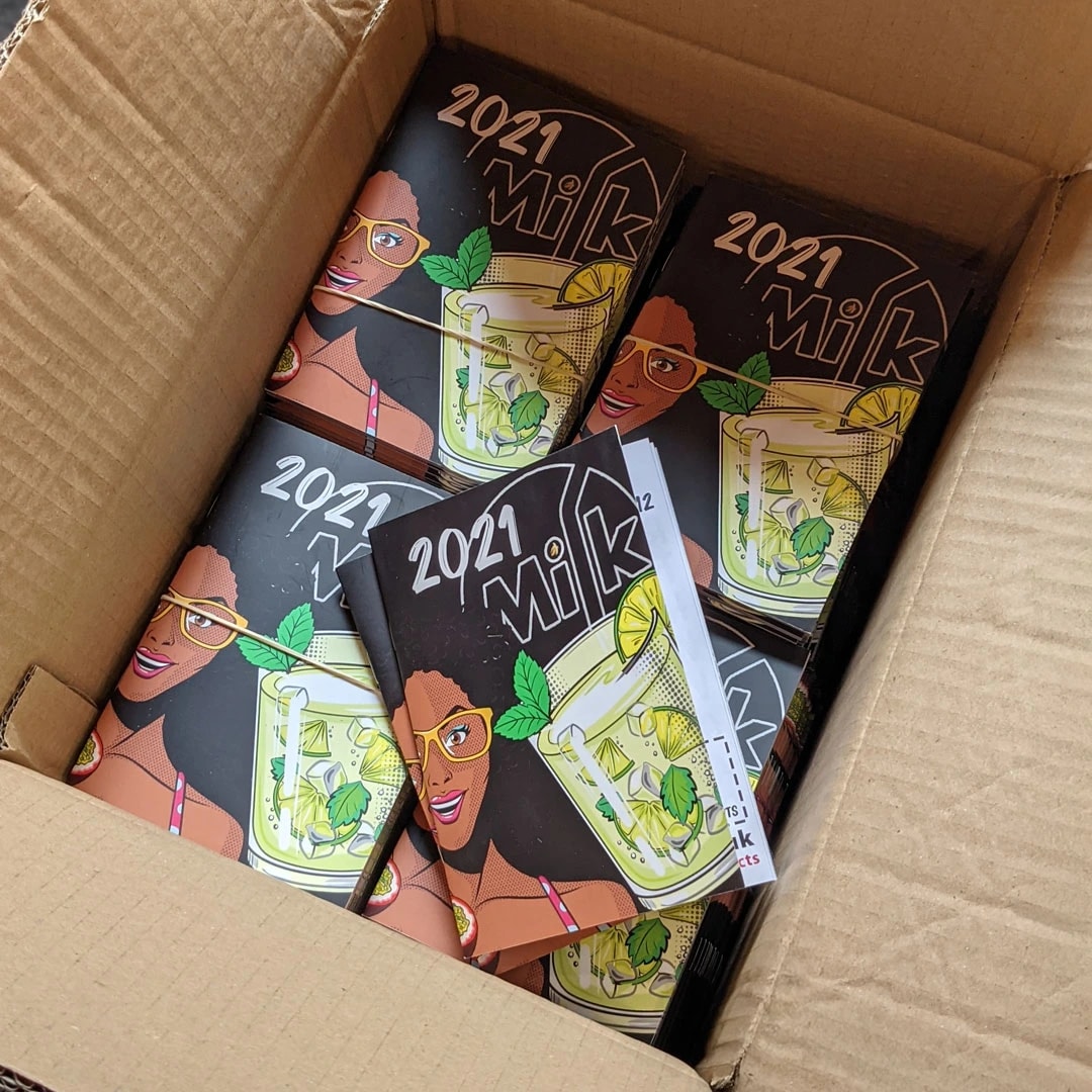 An open box filled with multiple Milk magazines featuring a drink and a woman on the cover.