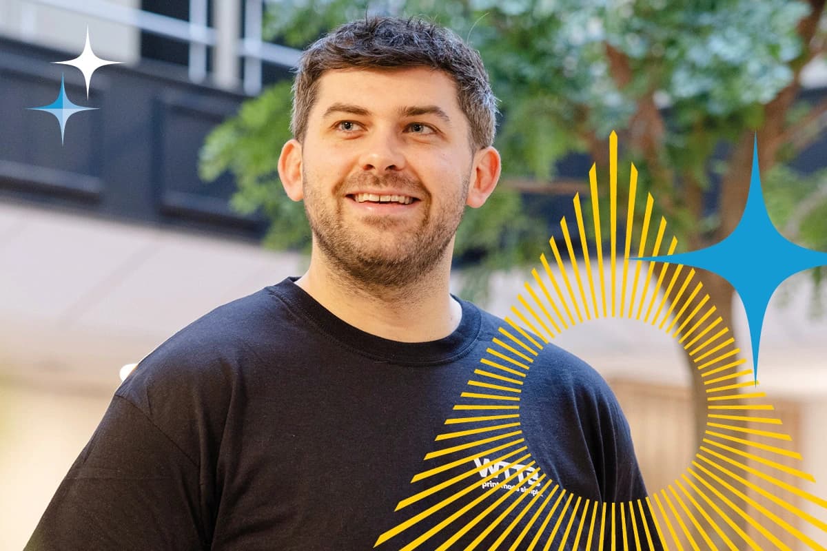 Man in a black t-shirt smiles indoors, with graphic star and sunburst overlays.