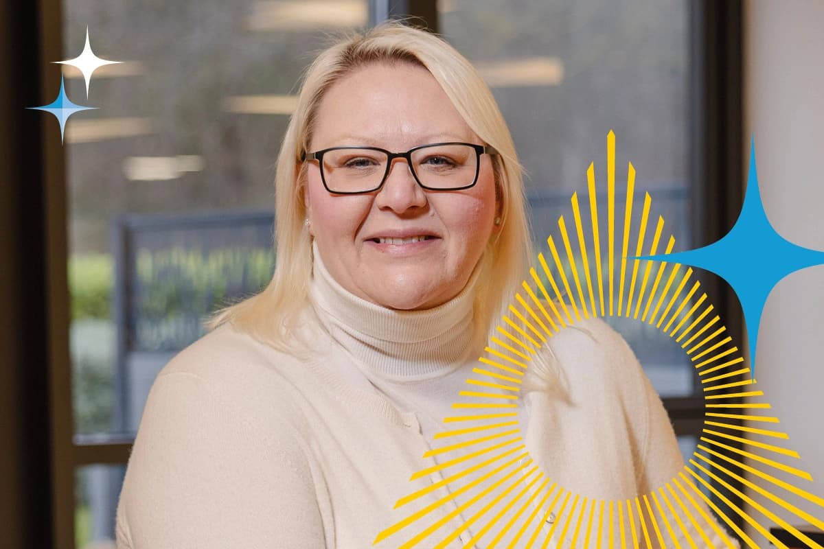 Woman with blonde hair and glasses smiling indoors, with graphic shapes overlayed on the image.