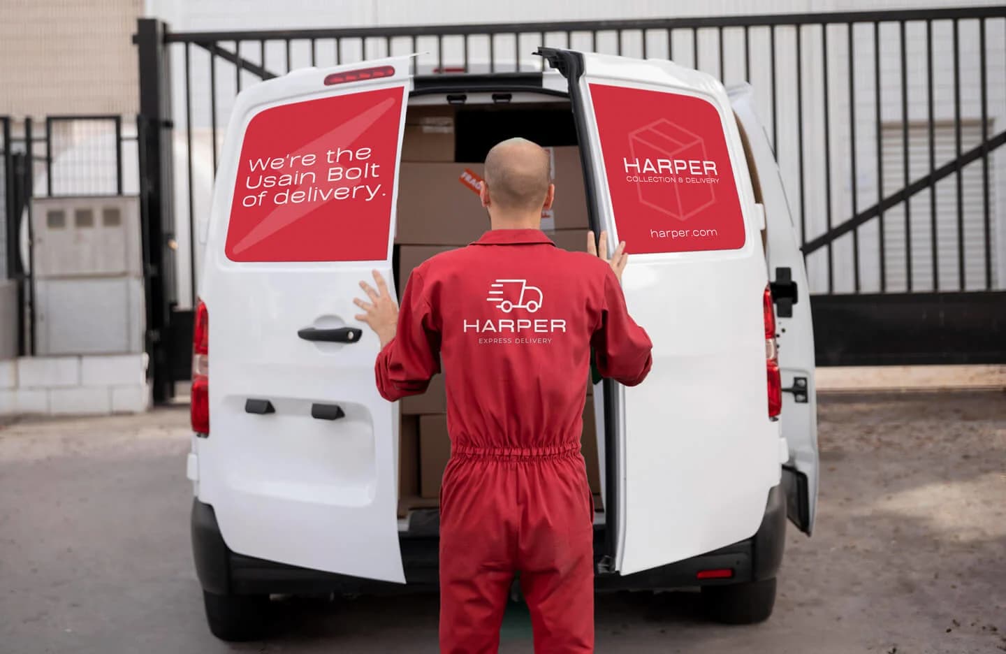 A man in a red jumpsuit stands beside a parked van with magnetic van signs on the doors