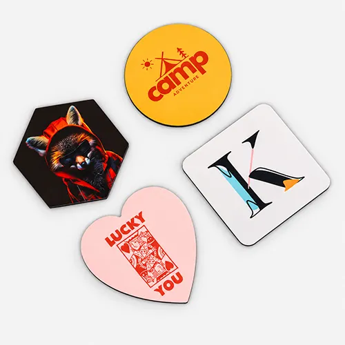 Four assorted coasters: a camp logo, a raccoon, the letter K, and a heart with "Lucky You.