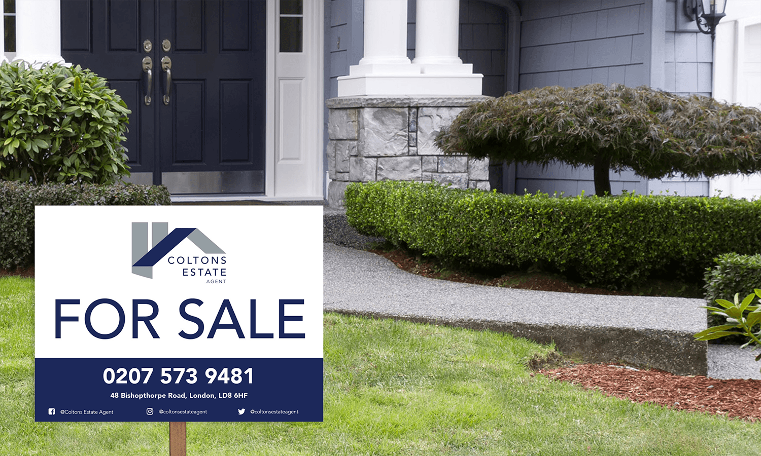 For sale estate agent sign in front of a house with a walkway, shrubs, and a stone porch.