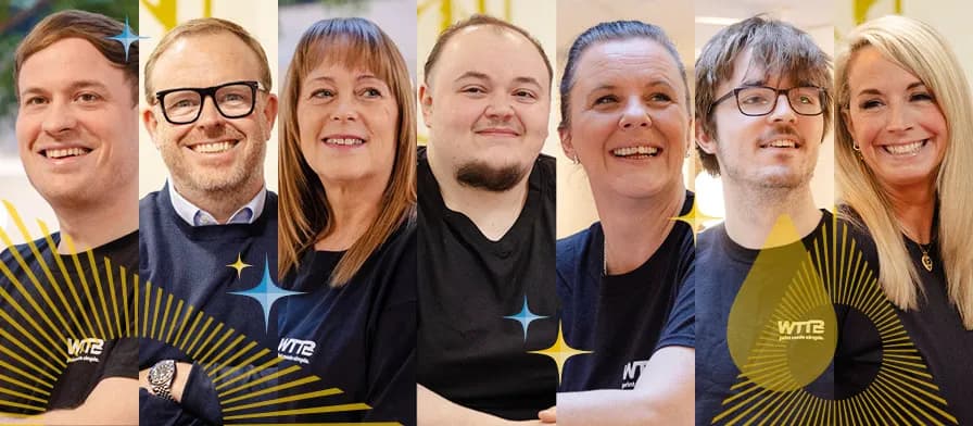 Group of seven people smiling, each wearing branded shirts.
