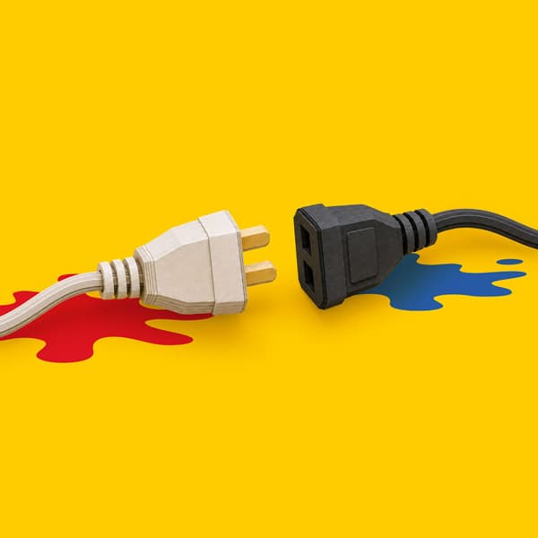 A UK plug and socket facing each other on a yellow background with red and blue paint splashes.