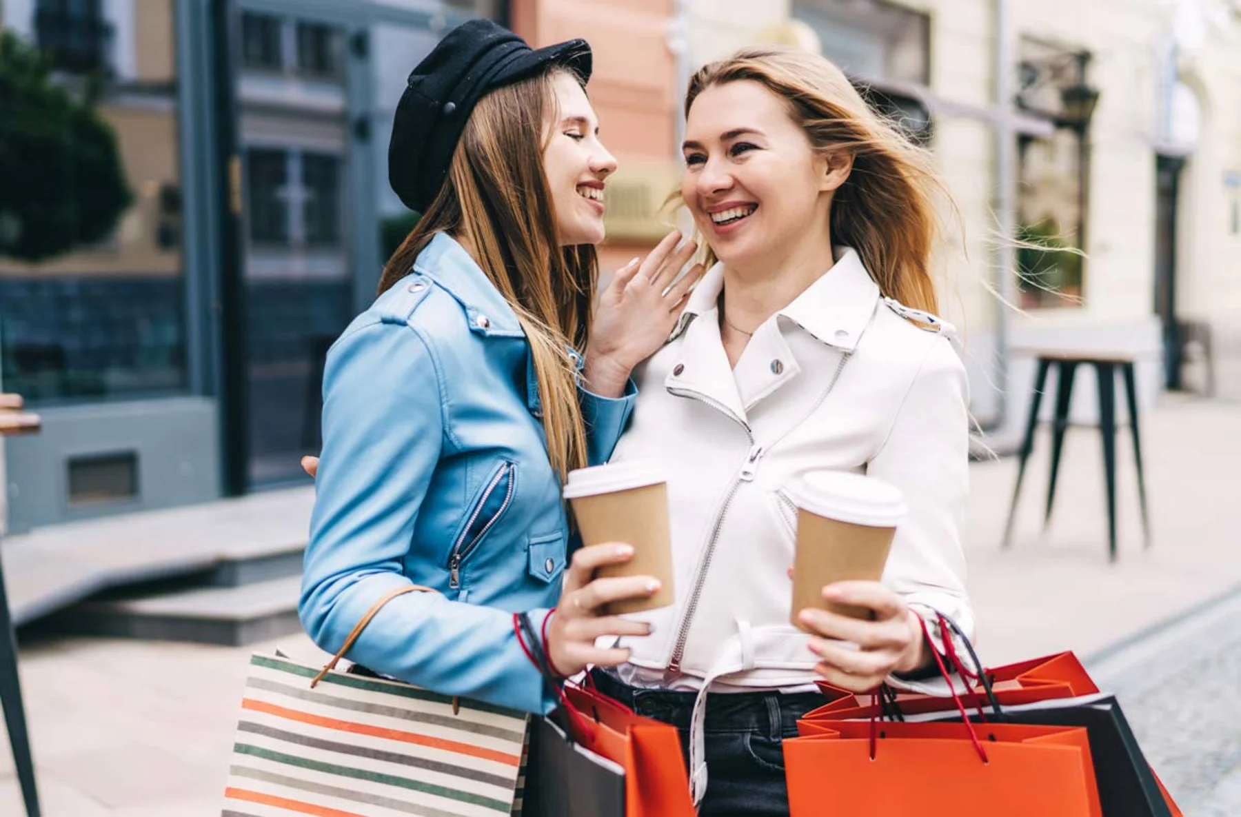 Two women engage in conversation while holding shopping bags