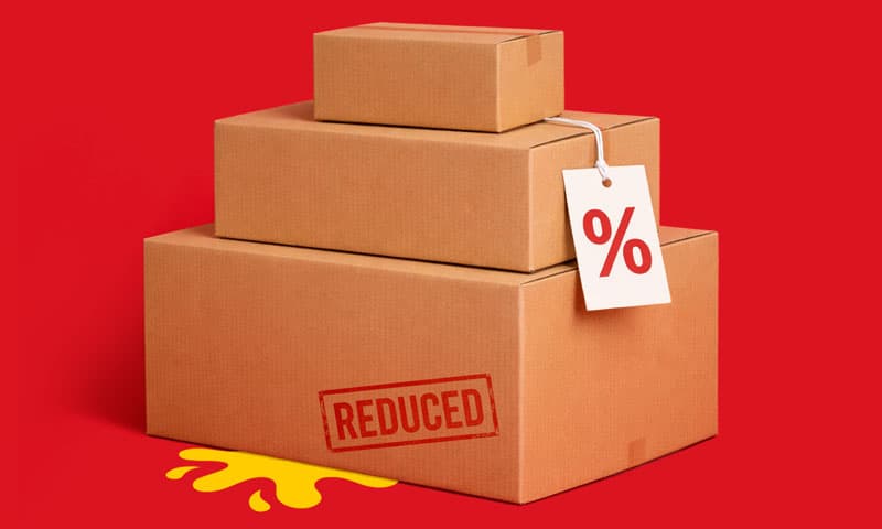 Three stacked cardboard boxes with a discount tag against a plain red background.