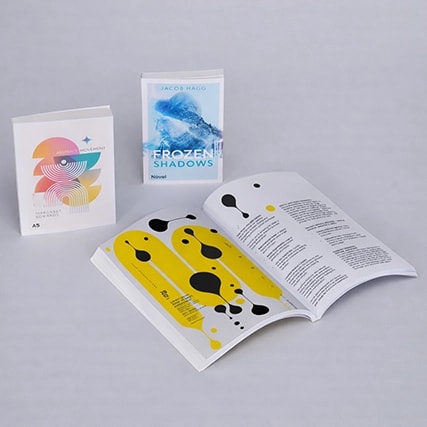 Three books displayed: one open, two closed, on a light gray surface.