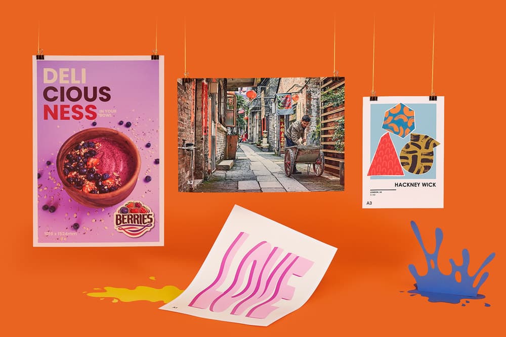 Three posters and a print hanging against an orange background with yellow and blue paint splatters.
